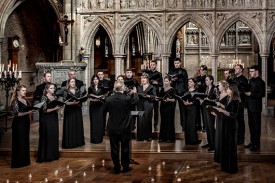 Group of people in a gothic looking space, in black clothing